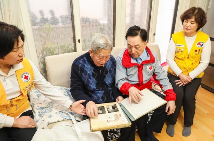 고령의 미상봉 이산가족인 이광진 어르신94세이 헤어진 동생들의 사진을 김철수 대한적십자사 회장오른쪽에서 두 번째에게 보여주며 담소를 나누고 있다